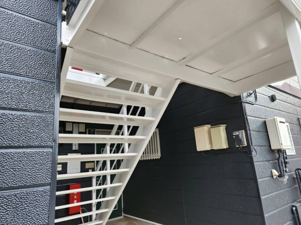 鉄骨階段部分の仕上がりです。付帯部をホワイトで統一することでダークトンの壁の色がとても際立ちます。錆びやすい鉄部には徹底した下地処理と塗装を施し、アパートの資産価値をしっかりと守ります。