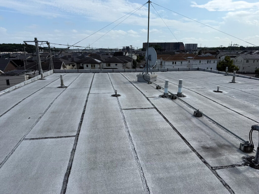 屋上全体の様子です。既存の防水シートが経年劣化により硬化しており、各所に細かな亀裂が発生していました。このまま放置してしまうと亀裂から雨水が侵入し、建物内部の腐食を招く恐れがあります。